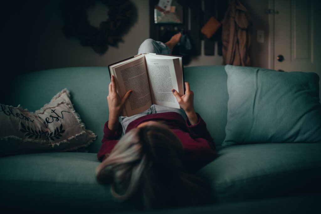 livros sobre luto. mulher lê livro no sofá.