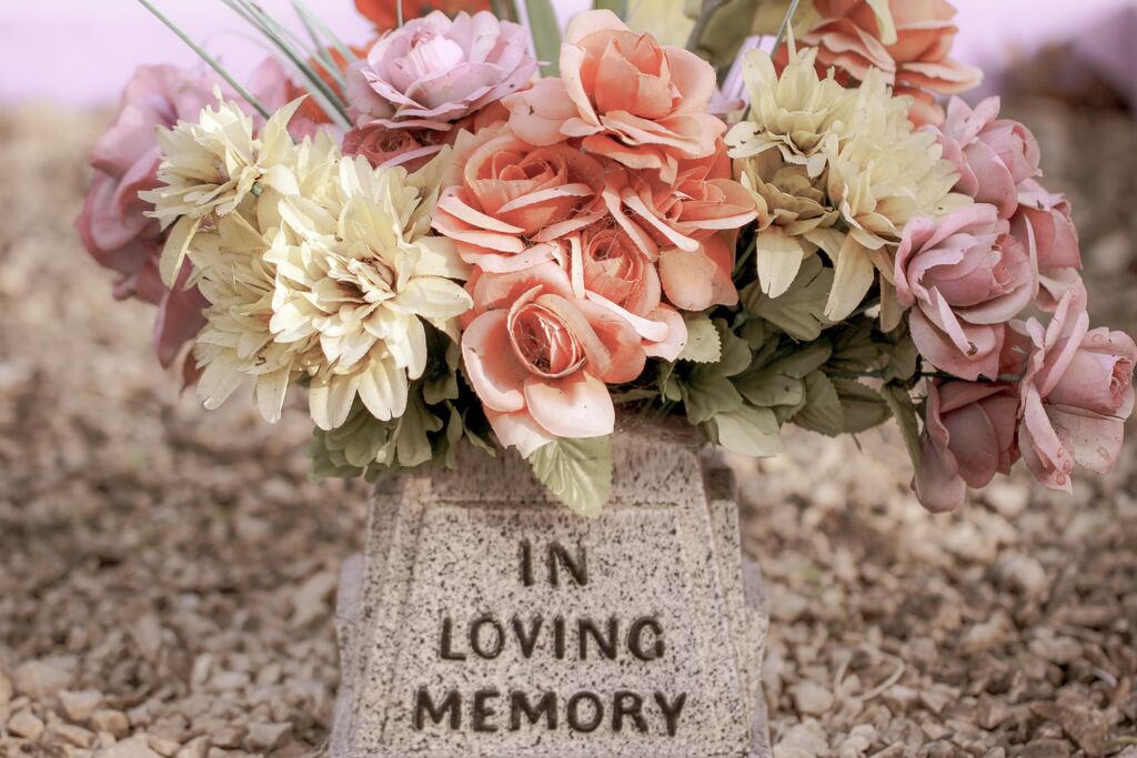 epitafio em túmulo com flores. lê-se "in loving memory"